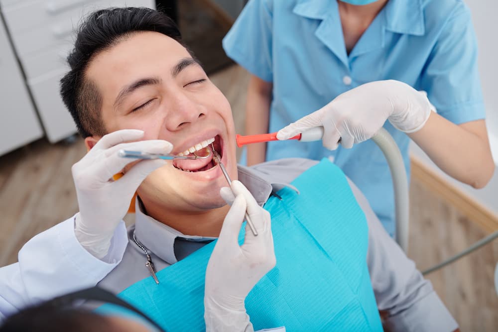 dentist-treating-teeth-of-patient-QMBDRY3